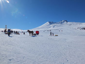People on snow covered land against sky