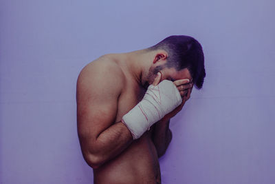 Side view of shirtless man against blue wall