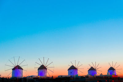Low angle view of windmills against clear blue sky at sunset