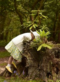 Girl looking into damaged tree stump in forest