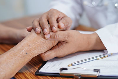 Midsection of doctor holding patient hands