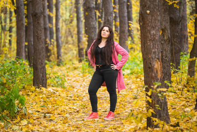 Full length portrait of woman standing in forest