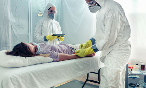 Doctors taking blood sample from patient lying on a gurney