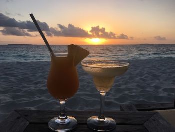 Close-up of cocktails on beach at sunset