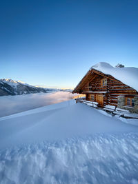 House on snowcapped mountain against sky at sunrise