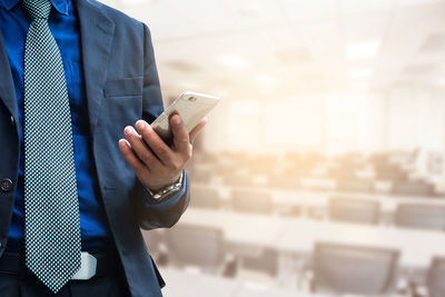 Midsection of man using mobile phone