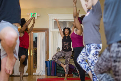 A class of yoga students raise their arms in a yoga pose