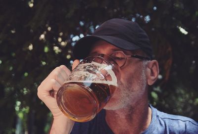 Man drinking beer in glass against tree