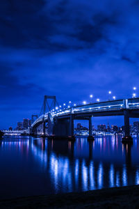 Illuminated bridge over river in city at night