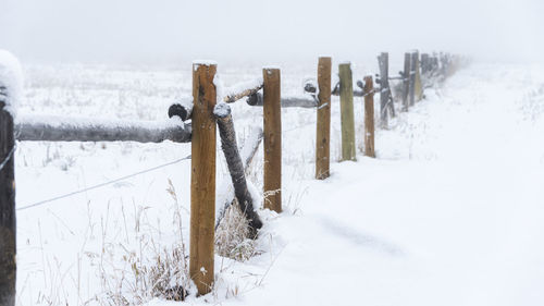 Wooden fence on snow covered field