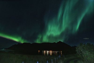 Scenic view of aurora borealis over mountain at night