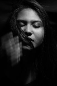 Close-up of young woman with eyes closed in darkroom