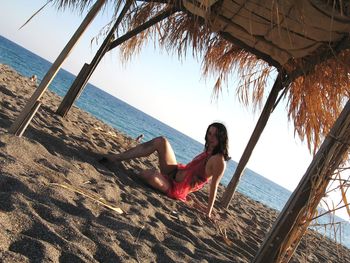 Woman sitting on beach against clear sky