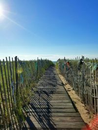 Wooden posts on field against clear blue sky