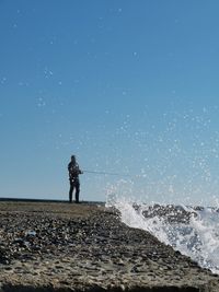 Man standing on shore against clear sky