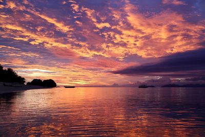 Scenic view of sea against dramatic sky during sunset