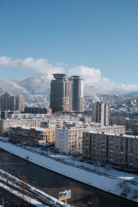 Snowy cityscape of sarajevo during a sunny day overlooking a mountain and a bussines center