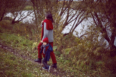 Mom and son go through the autumn forest next to the river