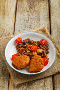 Cod cutlets with stewed potatoes and vegetables on a plate on a napkin on the table. vertical photo