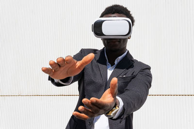 African american male standing experiencing virtual reality while using modern vr headset on yellow background in city