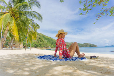 Man sitting on chair at beach against sky