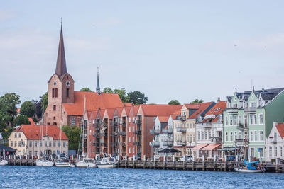 Sailboats in baltic sea by buildings against sky in city