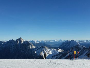 Person walking on snow covered mountain against clear sky