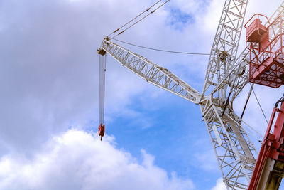 Crawler crane against blue sky and white clouds. real estate industry. red-white crane use reel lift 