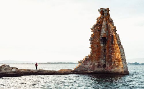 People on rock by sea against sky