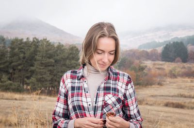 Beautiful woman standing on field against cloudy sky