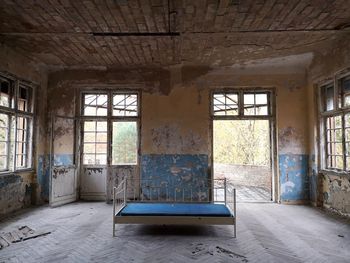 Interior of abandoned building with old sofa and big windows