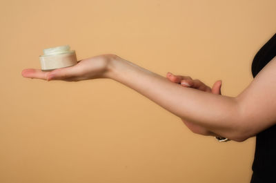 Midsection of woman holding jar against colored background