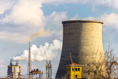 Smoke stacks emitting pollution against sky