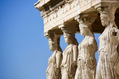 Low angle view of statues at old ruins against clear sky