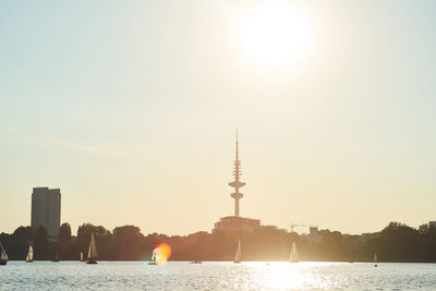 Water surface image of boats moving on river against sky during sunset