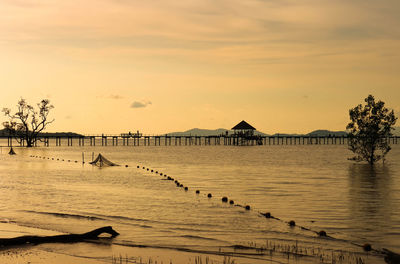 Sunsetting over the wooden bridge at the calm sea