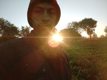 Portrait of man on field against bright sun