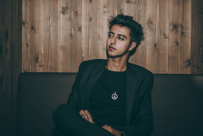 Young man looking away while sitting on sofa