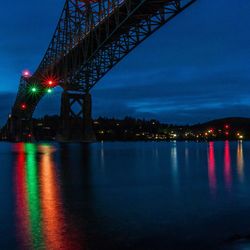 Illuminated bridge over river at night