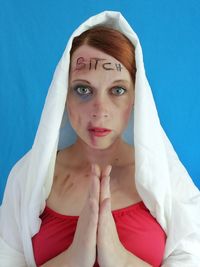 Portrait of woman with wounds standing against blue wall