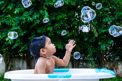 Full length of shirtless boy with bubbles