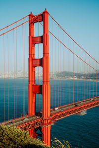 Suspension bridge over sea against clear sky