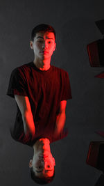 Portrait of young man standing against black background