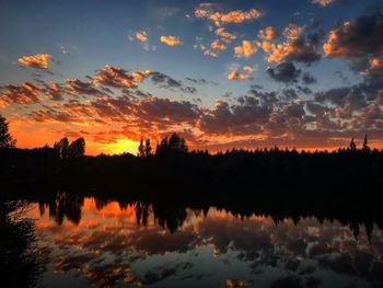 Silhouette trees by lake against sky during sunset