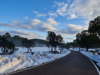 Scenic view of snow covered road against sky