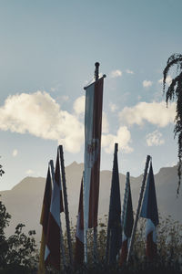 Panoramic view of wooden post and many flags against sky