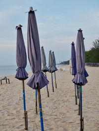 Deck chairs on beach against sky