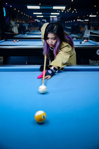 Portrait of young woman playing pool