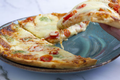 Close-up of hand taking a slice of pizza