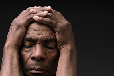 Black man praying to god on gray background with people stock image stock photo